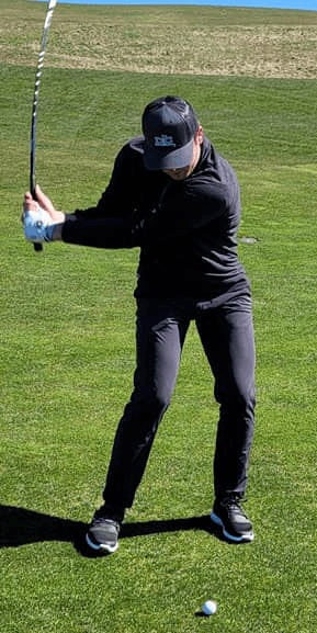 Student swinging while wearing a DC Golf hat